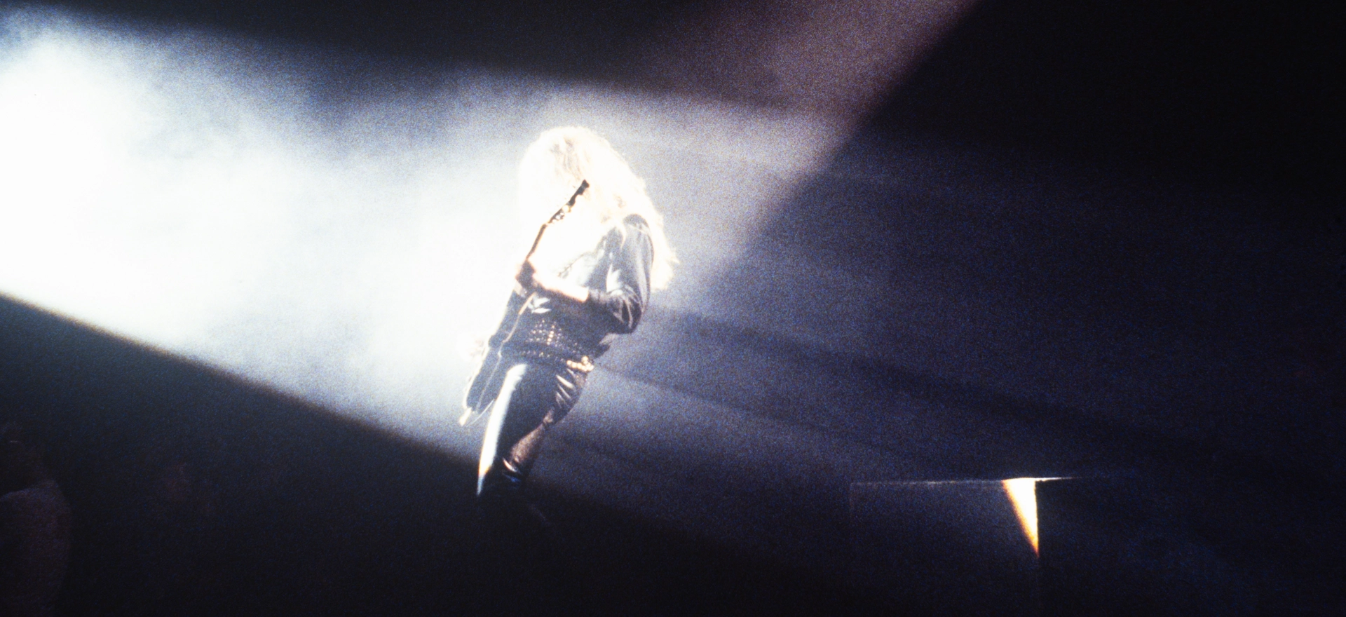 Scott Gorham of Thin Lizzy delivers an explosive guitar solo at the Hammersmith Odeon 1983 – white light, grainy, dry ice